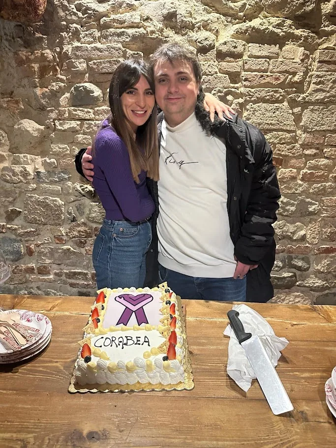 Francesco e Giorgia Bellini abbracciati dietro una torta con il logo e la scritta Corabea